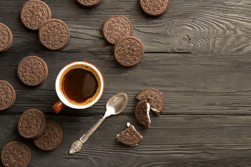 Black  coffee in the  brown ceramic cup and chocolate cookies on the black wooden background. Copy space.  Top view.