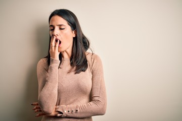 Young brunette woman with blue eyes wearing casual sweater over isolated white background bored yawning tired covering mouth with hand. Restless and sleepiness.