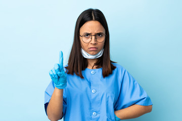 Surgeon woman over isolated blue background counting one with serious expression