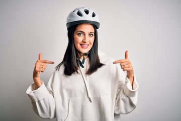 Young cyclist woman with blue eyes wearing bike helmet over isolated white background looking confident with smile on face, pointing oneself with fingers proud and happy.
