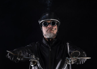 studio portrait of a vintage biker with a cigar on a black background