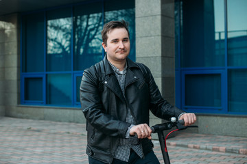 stylish man in urban background using electric scooter