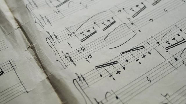 camera moves over the sheet with notes, close up, macro view, slider moving