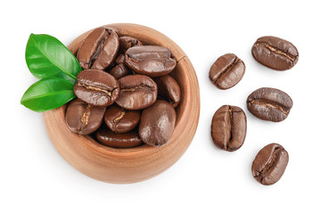 Heap of roasted coffee beans in wooden bowl with leaves isolated on white background with clipping path and full depth of field. Top view. Flat lay.