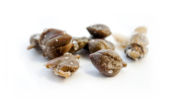 Capers in salt. Isolated on white. Selective focus.