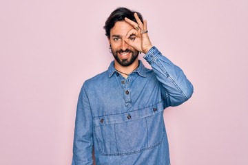 Fototapeta premium Young handsome hispanic bohemian man wearing hippie style over pink background doing ok gesture with hand smiling, eye looking through fingers with happy face.