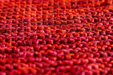 Knitted texture red color macro technique of scarf knitting with partial blur