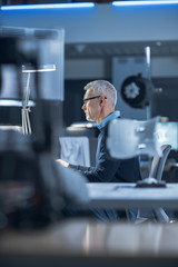 Shot of Industrial Engineer Working in Research Laboratory / Development Center, Using Computer. He is Working on New Efficient Engine Concept Design.