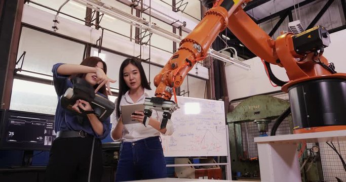 Engineers Team Control Robotic Arm Works and Moves. They are in a High Tech Research Laboratory with Modern Equipment. Technology and Innovation Concept.