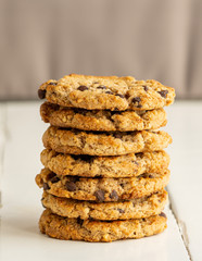 Stack of chocolate chips cookies, biscuits, shortbread on a white wooden table. Close up. Tasty crunchy dessert, breakfast, snack. Take away food. Bakery, tea, coffee house. Recipe, homemade. Vertical