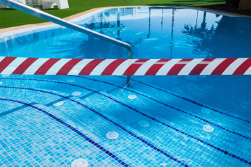 Fototapeta premium Red White warning tape pole fencing is protects for No entry (in the pool) . Ban on visiting public places (swimming pools, sports clubs). Ban on travel to resorts in other countries due to epidemic