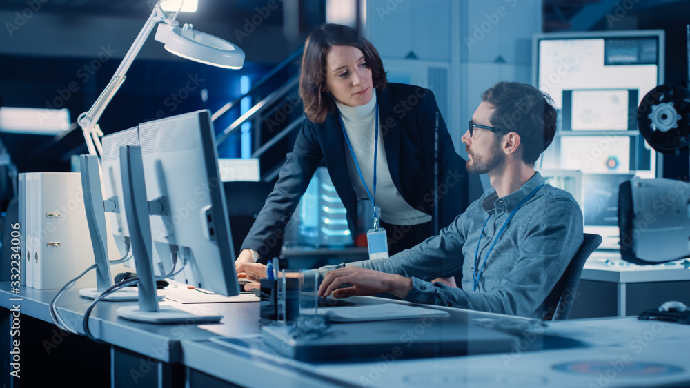 Poster Futuristic Machine Engine Development Engineer Working on Computer at His Desk, Talks with Female Project Manager. Team of Professionals Working in the Modern Industrial Design Institution