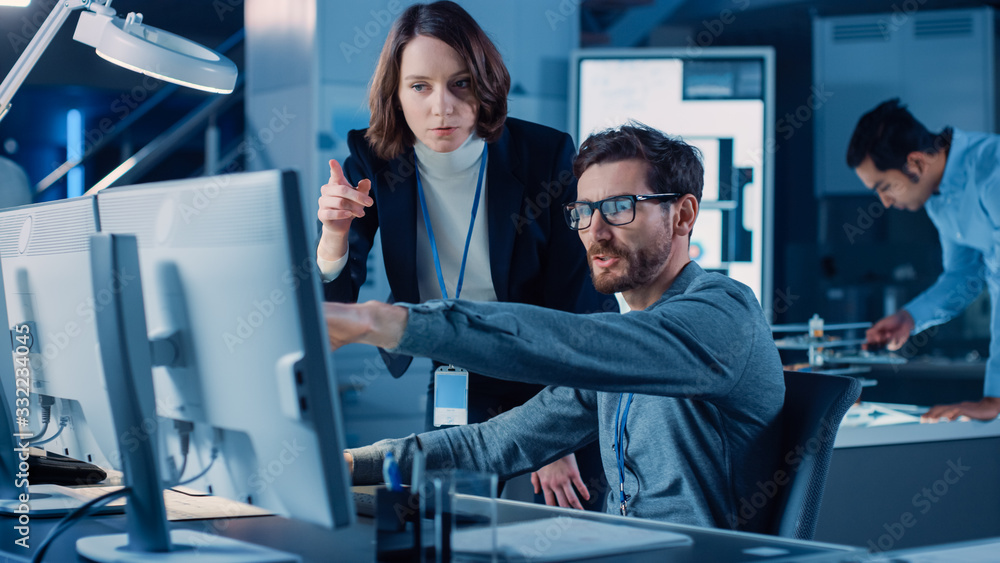 Poster Futuristic Machine Engine Development Engineer Working on Computer at His Desk, Talks with Female Project Manager. Team of Professionals Working in the Modern Industrial Design Institution