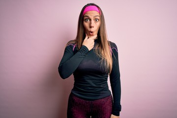 Young blonde fitness woman wearing sport workout clothes over isolated background Looking fascinated with disbelief, surprise and amazed expression with hands on chin