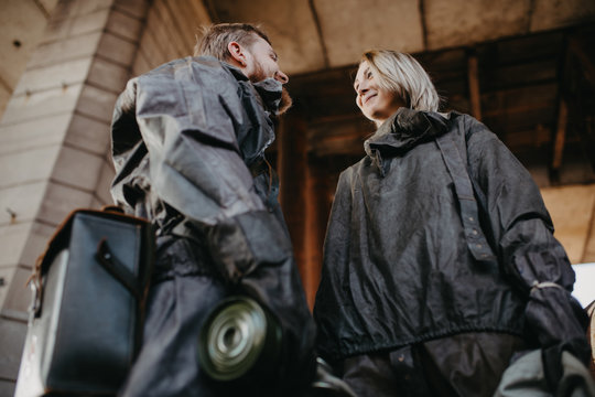 Couple in love stands in NBC protective suits and gas masks in their hands.