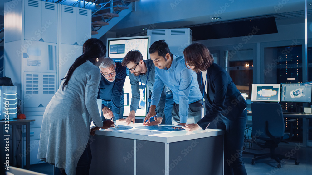 Poster Engineers Meeting in Technology Research Laboratory: Engineers Scientists and Developers Gathered Around Illuminated Conference Table, Talking and Finding Solution, Inspecting Industrial Engine Design
