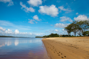 Panorama of a river beach with yellow sand stretching curved into the distance on a Sunny day against a turquoise sky. World tourism, landscape, tropics