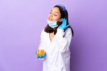 Scientist woman investigating a vaccine to cure coronavirus disease listening to something by putting hand on the ear