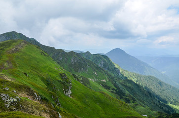 Ridge with grassy slopes and cliffs. Mountains of Marmarosy ridge in a far distance. Beautiful summer scenery of Ukraine
