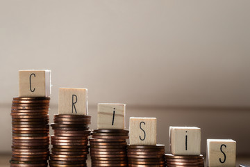 Wooden cubes with the word Crisis and pile of coins, money climbing stairs, business concept