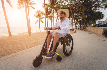 Disabled man in a wheelchair with electric scooter on the beach