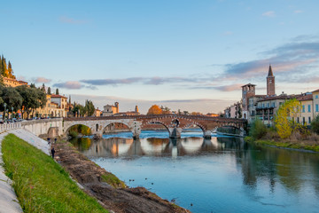 View at sunset of the ancient Roman arch Stone Bridge (Ponte Pietra) over the Adige River in Verona, Italy / APRIL 21, 2019