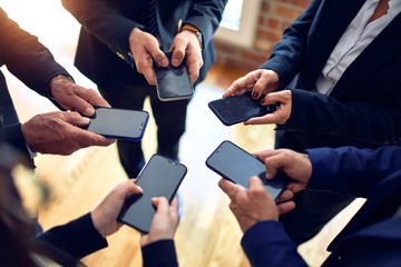 Group of business workers standing on a circle using smartphone together at the office.