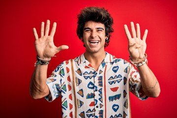 Young handsome man on vacation wearing summer shirt over isolated red background showing and...