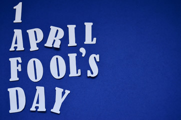 cut out letters April April Fool's Day on a blue background with copy space