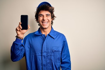 Young mechanic man wearing uniform holding smartphone over isolated white background with a happy face standing and smiling with a confident smile showing teeth - Powered by Adobe