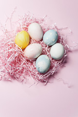 Painted eggs in pastel colors on a pink paper filler and background. Modern easter holiday template