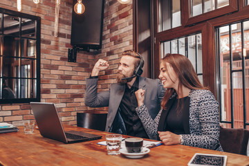 Happy excited business people celebrating success laughing and making yes gesture while looking at laptop monitor and getting great news