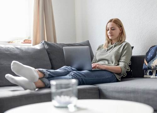 junge Frau mit laptop auf Sofa