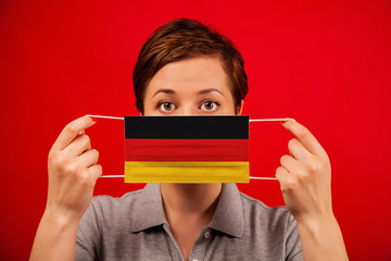 Coronavirus COVID-19 in Germany. Woman in medical protective mask with the image of the flag of...