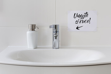 Sink with soap dispenser and note saying 