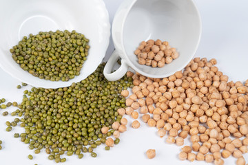 Green mung bean and Turkish peas poured from white cups on the table. Asian ingredients of traditional dishes.