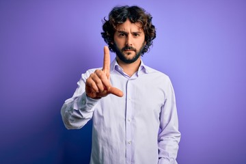 Young handsome business man with beard wearing shirt standing over purple background Pointing with finger up and angry expression, showing no gesture