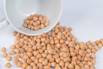 handful of large Turkish peas poured out of a white cup on a white table close-up. Macro shot. Traditional food ingredients