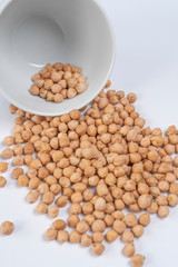 Turkish peas beans spilled out of a white cup on a white table close-up. Vertical view