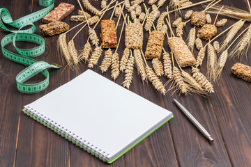 Fototapeta na wymiar Balanced protein granola bar. Spikelets of wheat, notebook and pen