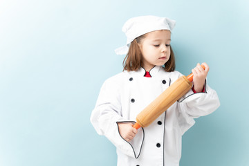 Gorgeous little girl wearing a chef uniform and aspiring to be a chef in a studio