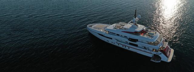 Aerial drone top down photo of luxury yacht with wooden deck anchored in open ocean sea