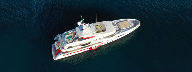 Aerial drone top down photo of luxury yacht with wooden deck anchored in open ocean sea