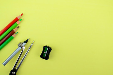 A black pencil sharpener ,a pencil attached to a pencil compass and four pencil crayon scattered on a paper