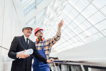 Foreman shows the work done to the client. A businessman inspects the constructed glass roof...