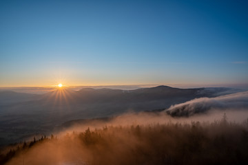 Fototapeta na wymiar Sunrise in the mountains looking at Pustevny with a beauty mist in the valley, Czech Pustevny