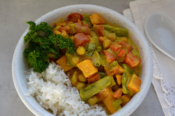 Veganes Süßkartoffel-Kichererbsen-Curry mit Zuckerschoten und Reis auf hellem Hintergrund