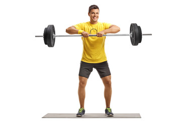 Fototapeta na wymiar Young man lifting weights on an exercise mat