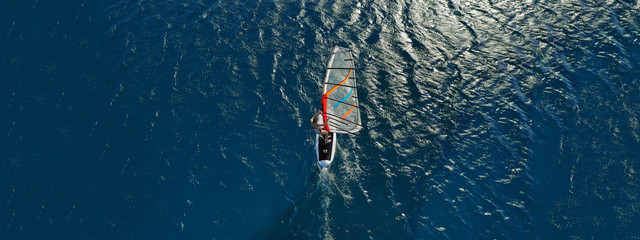 Aerial drone ultra wide photo of wind surfer cruising in high speed in tropical exotic bay