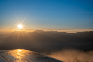 Sunrise in mountains with fog in valley with beautiful reflection of parsk on wood, Czech Beskydy